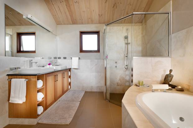 A wonderfully bright white tiled bathroom with spa, shower and wooden vanity.