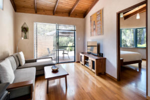 The lounge of Rumi with a comfortable couch, wooden floors and a large door to the outside.
