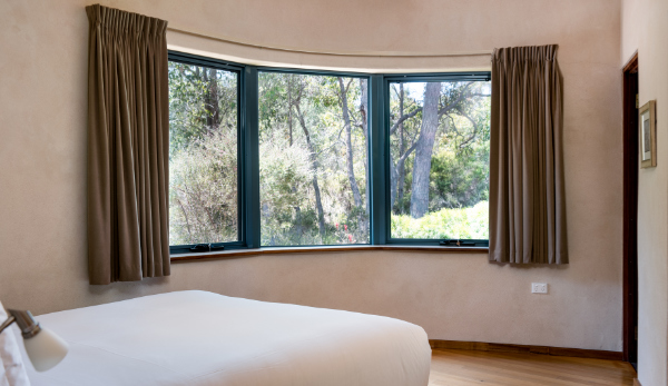 White bed spread with a view into the forrest