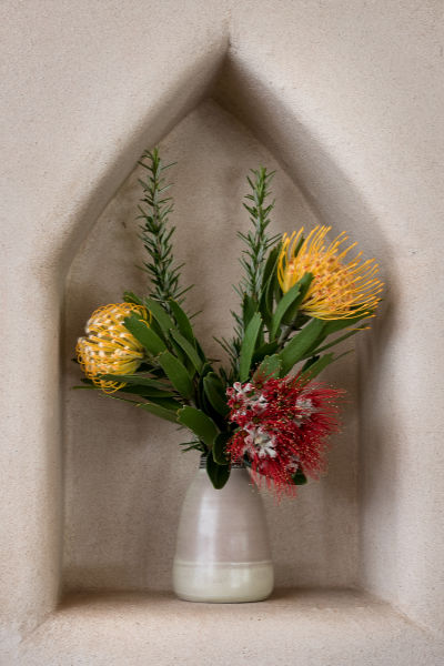 Native flowers in a vase in a niche in the rendered wall