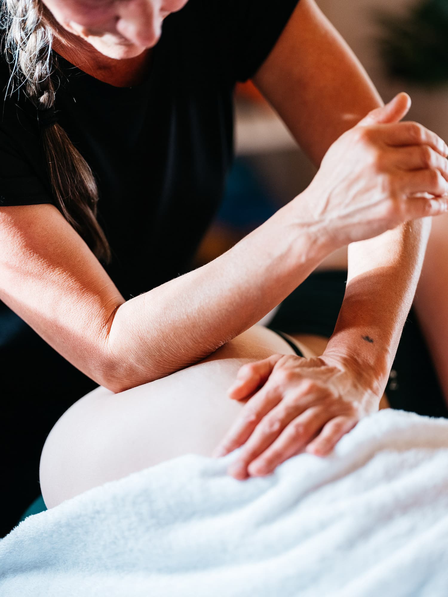A massage therapist uses her elbow in the hip of a client.